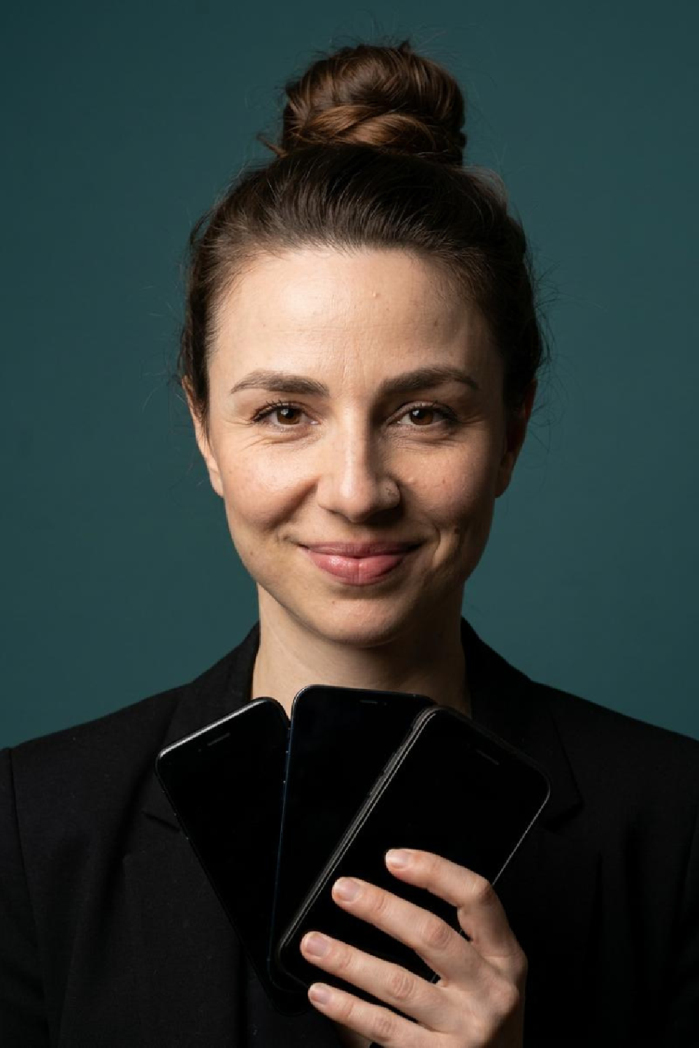 Dr. Maria Kliesch hält drei Smartphones wie einen Kartenfächer in der Hand